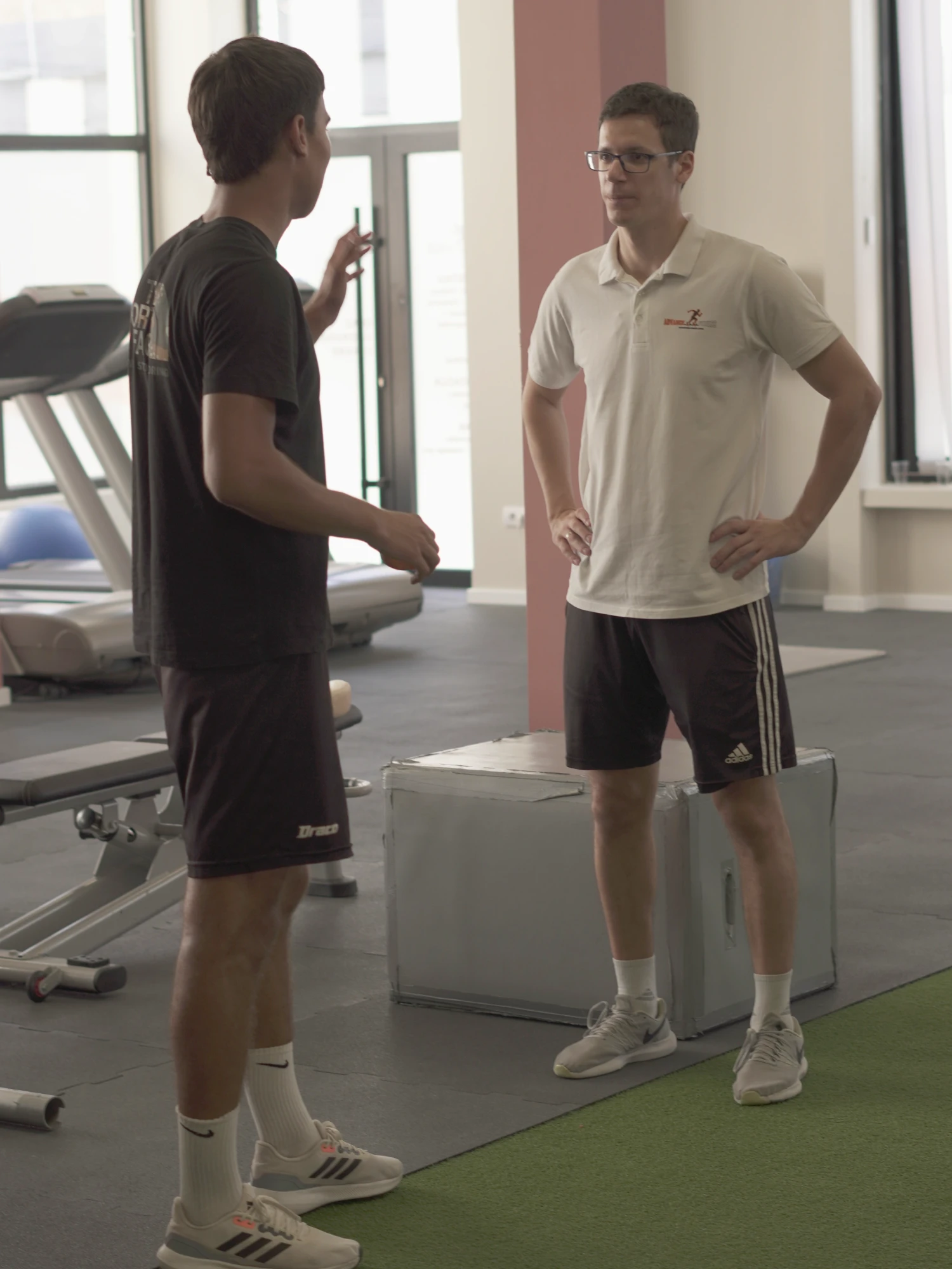 Trener Advance Fitness Centra razgovara sa klijentom u sali na Novom Beogradu, pored kutija za skokove i staze od veštačke trave.